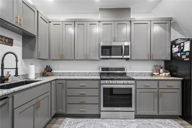 kitchen featuring light stone counters, gray cabinetry, stainless steel appliances, sink, and dark hardwood / wood-style floors