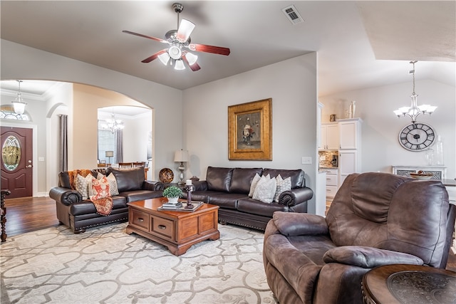 living room featuring vaulted ceiling, light hardwood / wood-style flooring, ceiling fan with notable chandelier, and ornamental molding