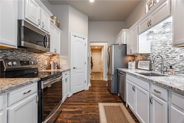 kitchen featuring white cabinetry, sink, light stone counters, dark hardwood / wood-style floors, and appliances with stainless steel finishes