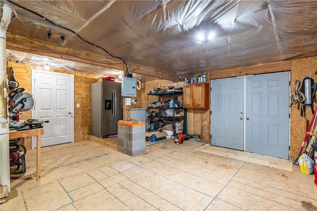 basement with a workshop area, stainless steel refrigerator with ice dispenser, and electric panel