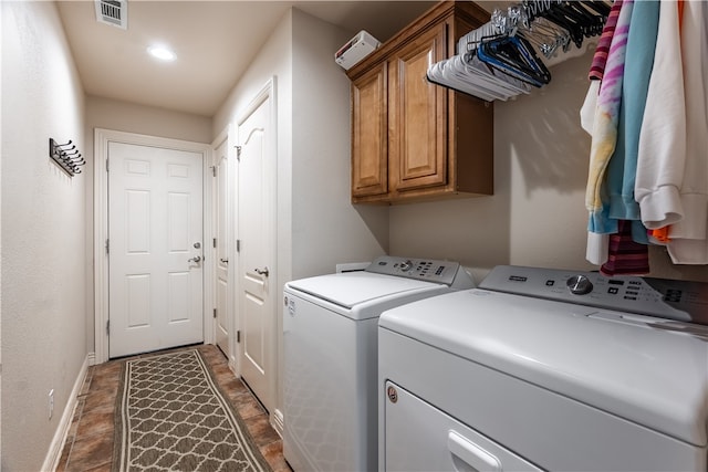 clothes washing area with washer and clothes dryer and cabinets