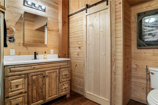 bathroom with toilet, vanity, and wooden walls