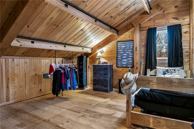 unfurnished bedroom featuring wood walls, wooden ceiling, light wood-type flooring, a closet, and lofted ceiling with beams