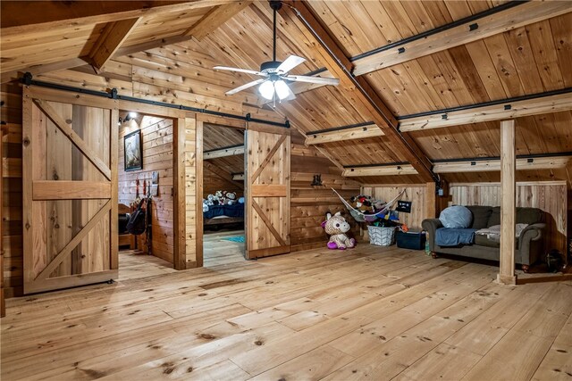 bonus room featuring vaulted ceiling with beams, wood walls, wooden ceiling, light hardwood / wood-style flooring, and a barn door