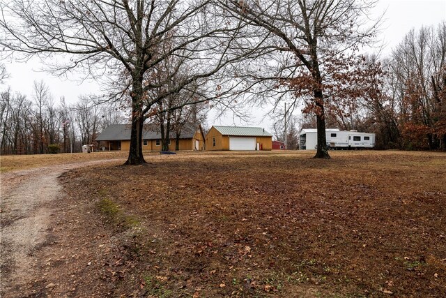 exterior space with a garage, metal roof, and dirt driveway