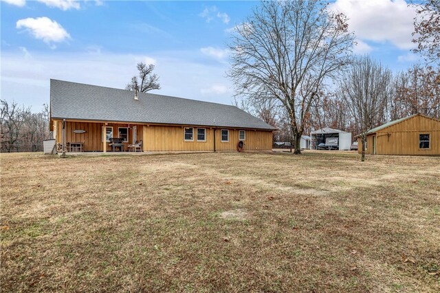 rear view of property featuring a yard and an outbuilding