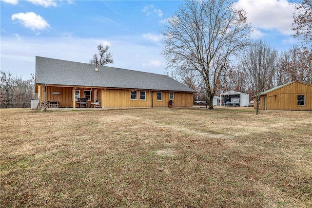 back of property featuring an outdoor structure and a lawn