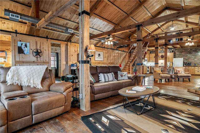 living room with dark wood-type flooring, wood walls, lofted ceiling with beams, ceiling fan, and a barn door