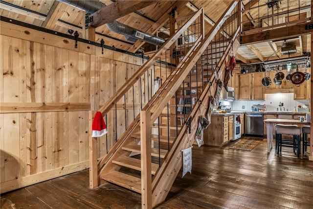 staircase with wood ceiling, hardwood / wood-style floors, wooden walls, beam ceiling, and sink