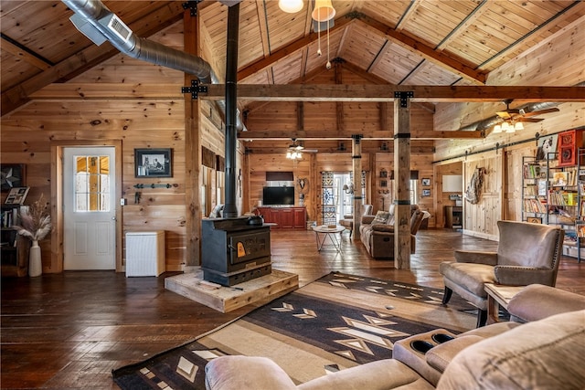 living area with wooden walls, dark wood-type flooring, a healthy amount of sunlight, a wood stove, and a barn door