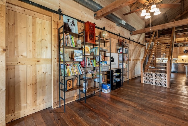 interior space featuring a barn door, stairway, wooden walls, dark wood-type flooring, and a ceiling fan