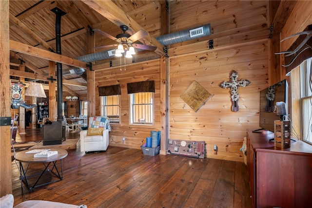 interior space featuring wooden walls, dark wood finished floors, a wood stove, and vaulted ceiling with beams