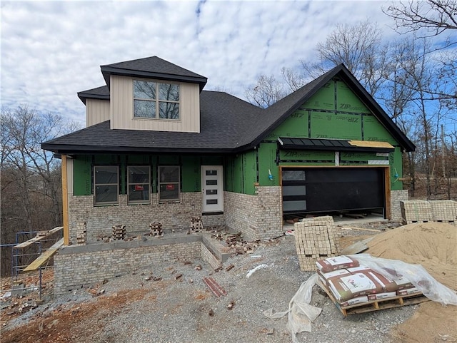 view of front facade featuring roof with shingles, brick siding, and an attached garage