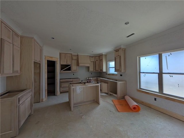 kitchen with a textured ceiling, light brown cabinets, a kitchen island, and premium range hood