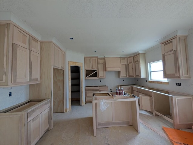 kitchen with a textured ceiling, light brown cabinets, and a center island