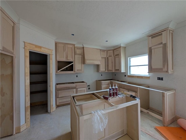 kitchen featuring custom range hood, a kitchen island, a textured ceiling, and light brown cabinets