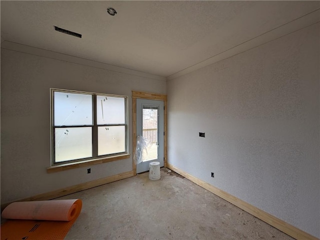 empty room with crown molding, concrete floors, and baseboards