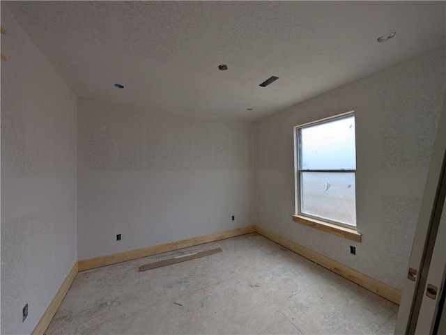 empty room featuring baseboards and a textured ceiling