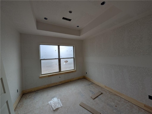 unfurnished room featuring a raised ceiling and baseboards