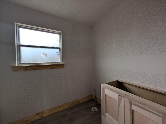 washroom with a textured ceiling and baseboards