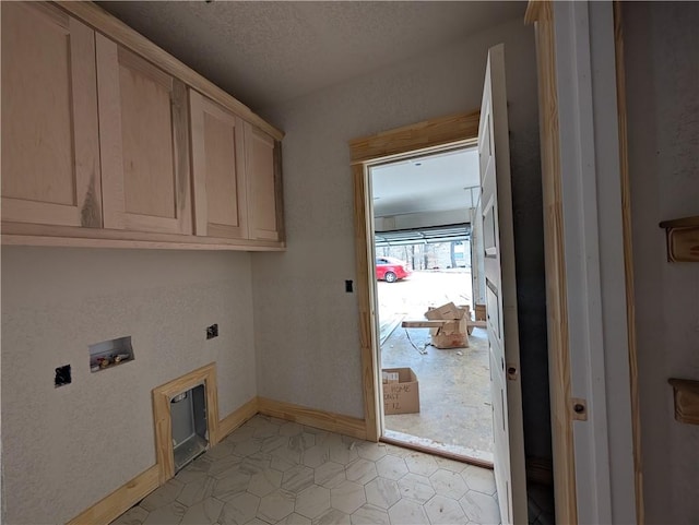 laundry area with a textured ceiling, hookup for a washing machine, hookup for an electric dryer, baseboards, and cabinet space