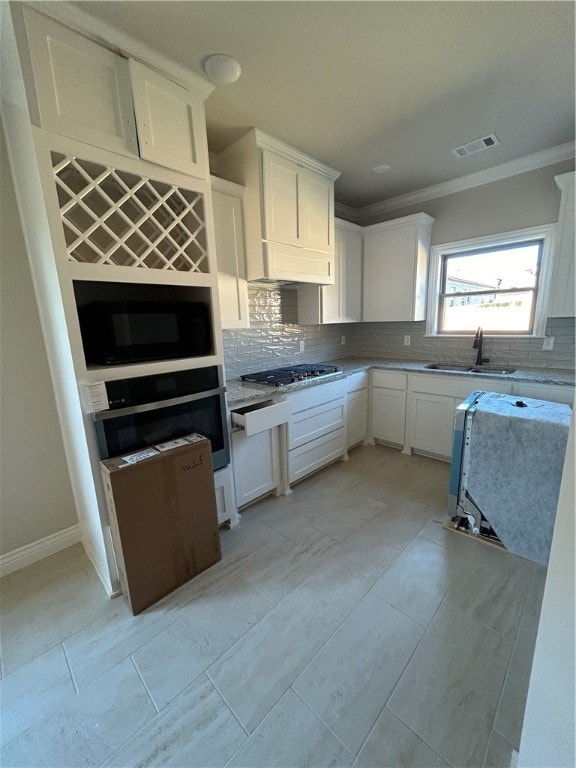 kitchen featuring white cabinets, appliances with stainless steel finishes, tasteful backsplash, and sink