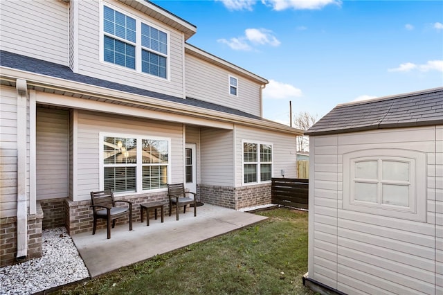 rear view of property featuring a patio area, a yard, and a storage shed