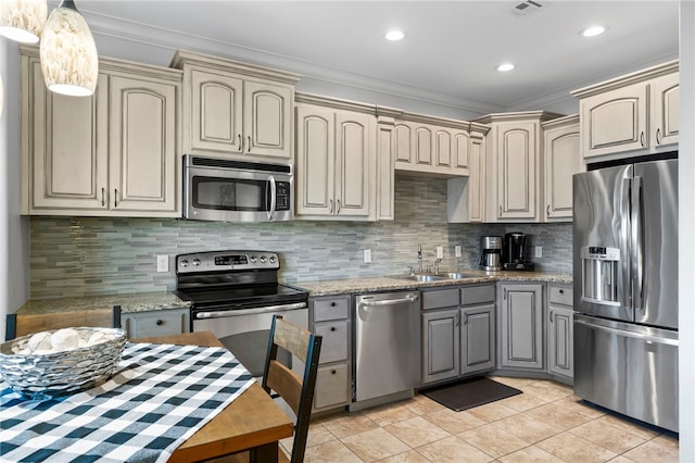 kitchen featuring light stone countertops, appliances with stainless steel finishes, decorative backsplash, and ornamental molding