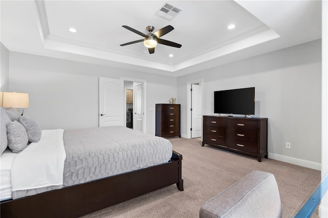 bedroom featuring ceiling fan, light colored carpet, and a tray ceiling