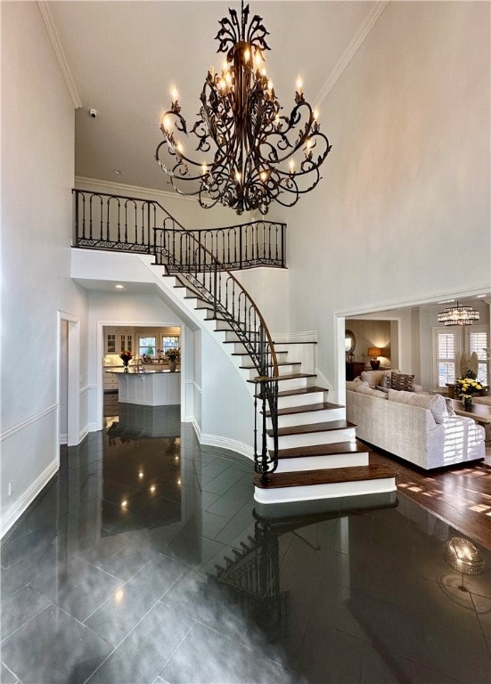 staircase featuring tile patterned flooring, a towering ceiling, a chandelier, and ornamental molding