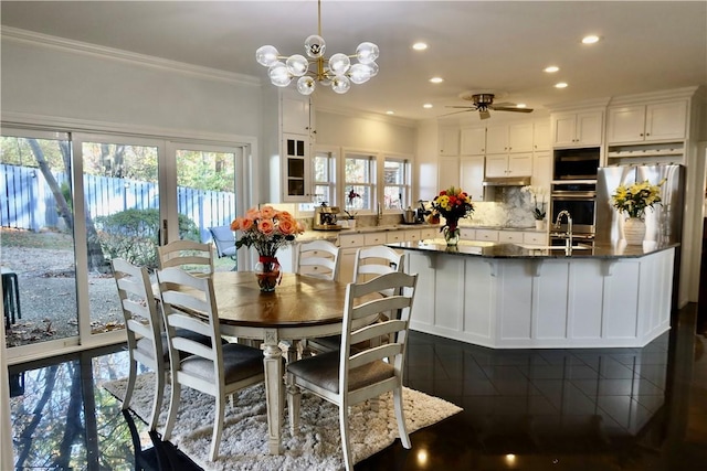 dining room with crown molding, sink, a healthy amount of sunlight, and ceiling fan with notable chandelier