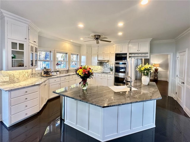 kitchen with white cabinetry, crown molding, stainless steel appliances, and a large island