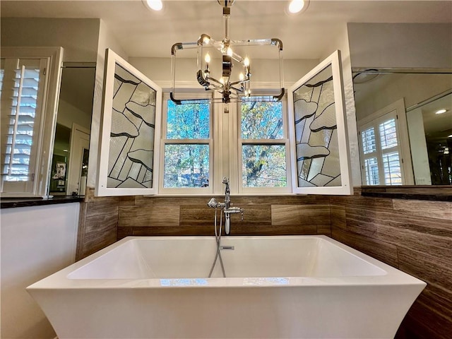 bathroom featuring a notable chandelier, plenty of natural light, sink, and a tub