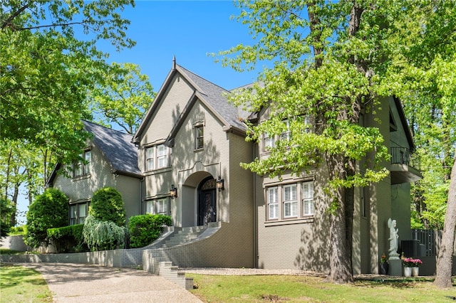 tudor home featuring brick siding and a balcony