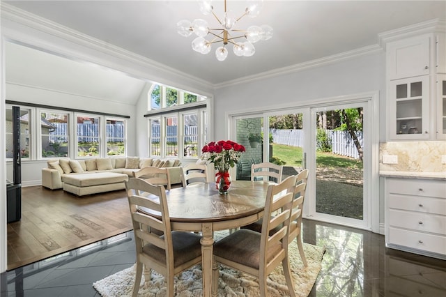 dining room featuring crown molding, dark tile patterned floors, a notable chandelier, and vaulted ceiling