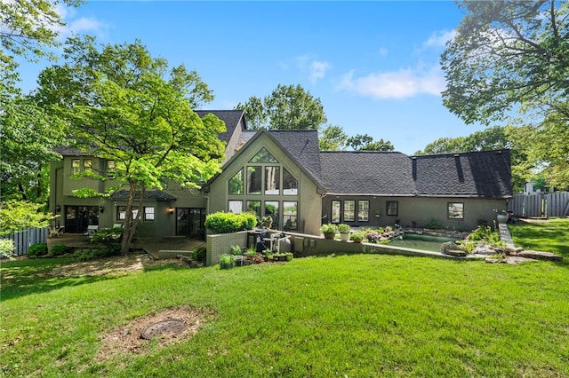 back of property featuring a lawn and fence