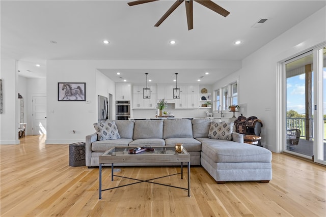 living room with light hardwood / wood-style floors, ceiling fan, and sink