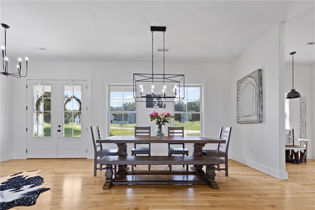 dining space featuring french doors, light hardwood / wood-style floors, and an inviting chandelier