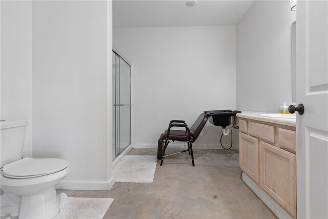 bathroom featuring a shower with door, vanity, concrete floors, and toilet