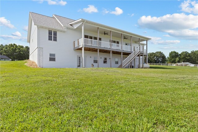 rear view of property with ceiling fan and a yard