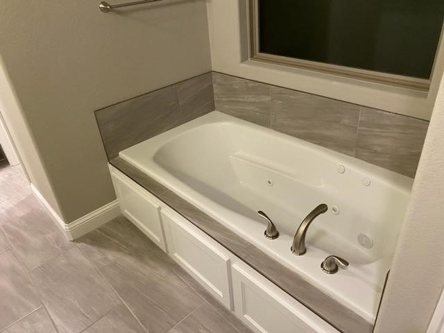 bathroom with a tub to relax in and tile patterned floors