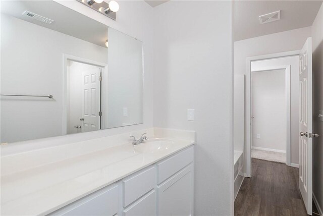 bathroom featuring vanity, wood-type flooring, and a tub