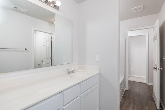 bathroom with a bathtub, visible vents, vanity, and wood finished floors