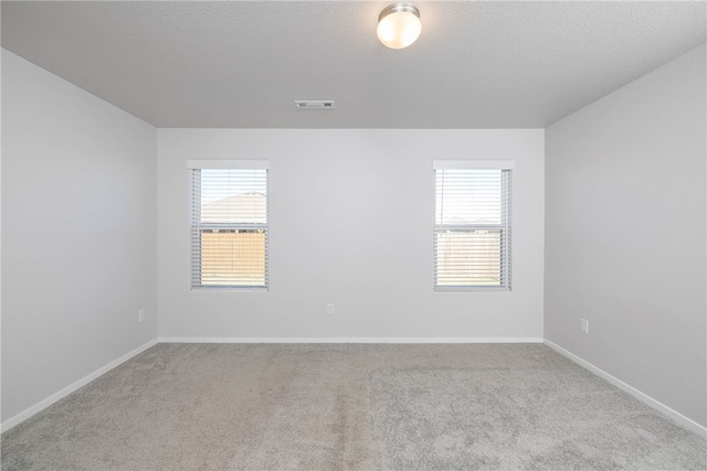 spare room with a textured ceiling and light colored carpet