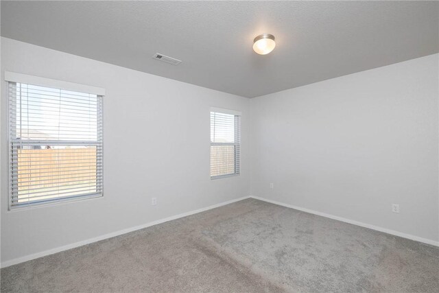 carpeted spare room with a textured ceiling