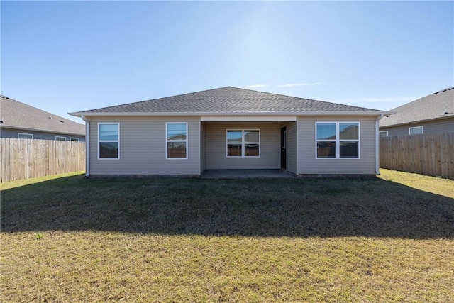 rear view of property featuring a patio, a lawn, roof with shingles, and a fenced backyard