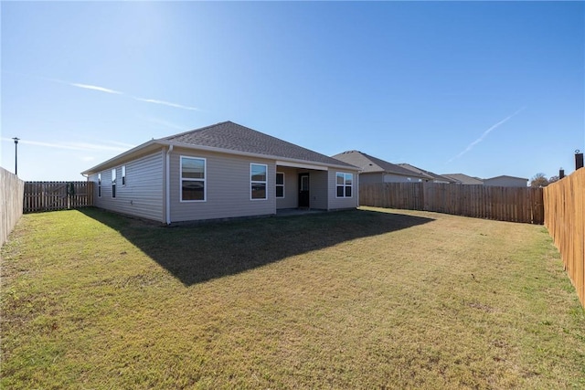 rear view of property featuring a fenced backyard and a yard