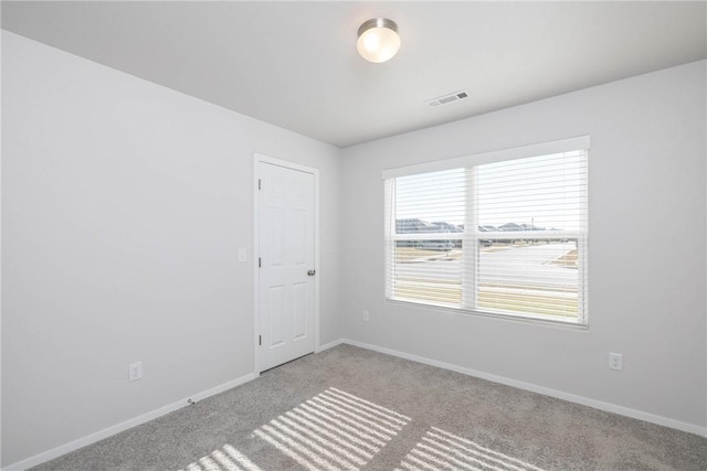 carpeted empty room with visible vents and baseboards