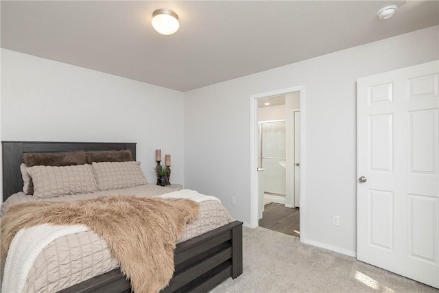 bedroom featuring light colored carpet, baseboards, and connected bathroom