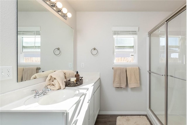 full bathroom featuring a sink, baseboards, a shower with door, and double vanity